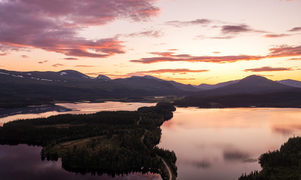 Flygbild på ett fjällandskap. I fjärran syns berg, i förgrunden sjö och skog.