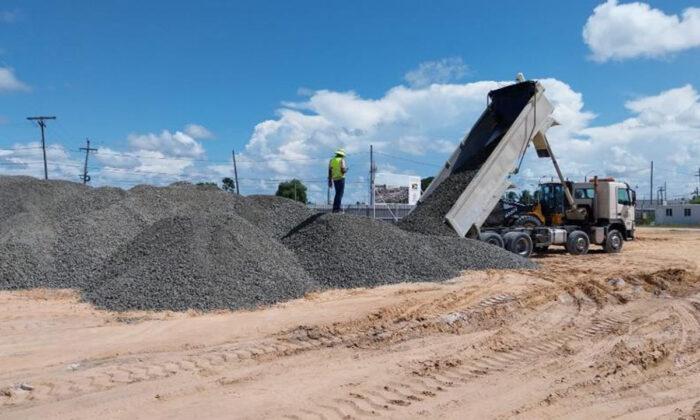 Bilden visar en byggarbetsplats i Guyana. En lastbil tippar grus på platsen.